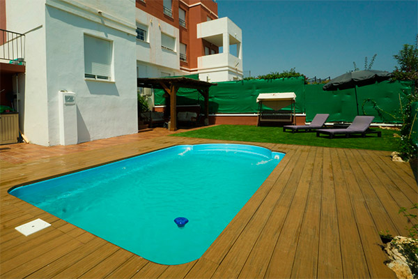 Piscina con tarima exterior sintética y césped artificial